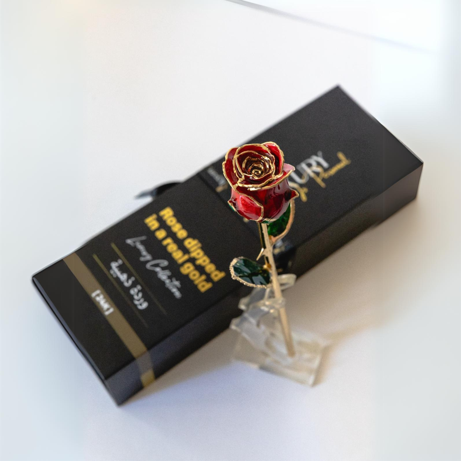 24k gold dipped rose red on a stand next to the box